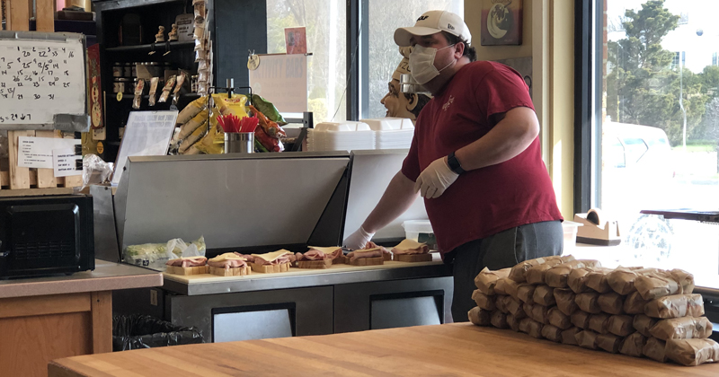 An employee from Great Harvest Bread Co. makes sandwiches